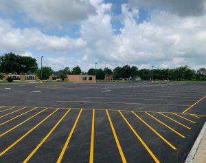 Exterior shot of GHS in the background, in the foreground is newly paved parking lot with parking spots marked with yellow paint lines.