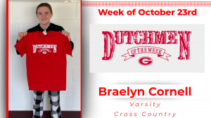 Student is standing in front of a white wall holding a red t-shirt that reads Dutchmen of the Week