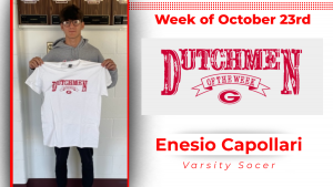 Student is standing in front of a white wall, holding a white t-shirt with red lettering that reads Dutchmen of the Week