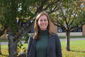 New administrator stands in front of trees outside of GHS, smiling at the camera