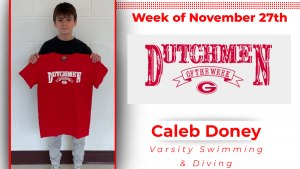Student is standing in front of a white wall, holding a red t-shirt with white writing that says Dutchmen of the Week