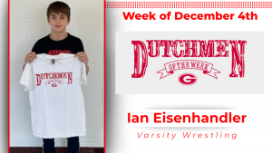 Student standing in front of a white wall, holding a white t-shirt with red lettering that reads: Dutchmen of the Week