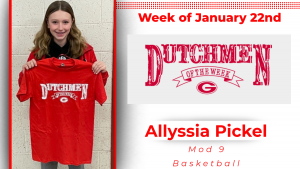 A student stands in front of a white wall holding a red t-shirt with white lettering that reads Dutchmen of the Week