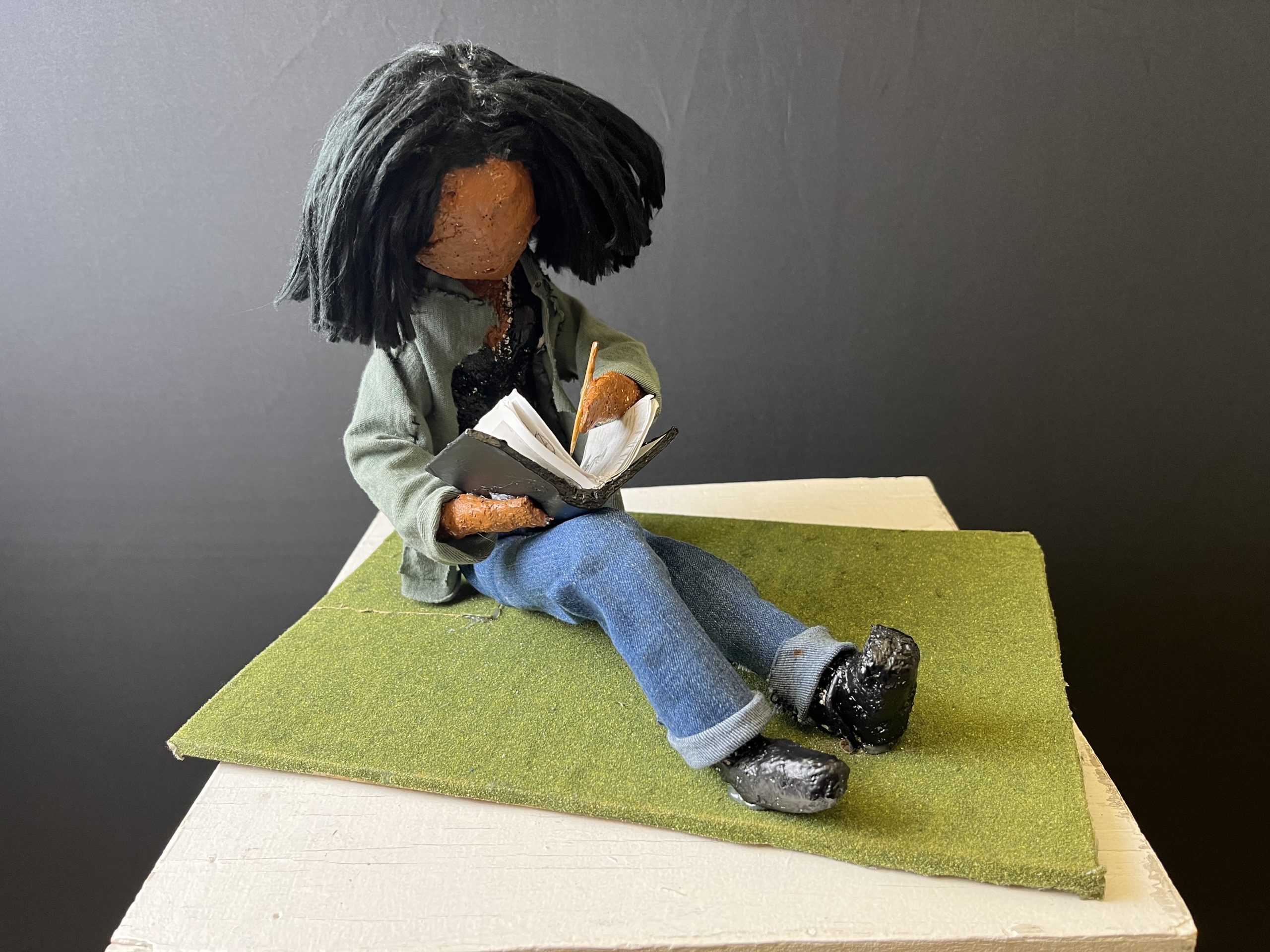 Student artwork; a sculpture of a student writing in a notebook