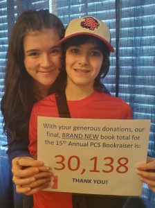 Two young people stand together. They are holding a piece of paper that reads: With your generous donations, our final, Brand New book total for the 15th annual PCS bookraiser is: 30,138 Thank you!