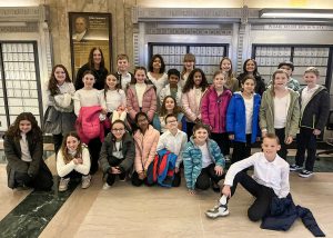 The LES Chorus standing with their teacher for a group photo in the hallway of the U.S. Courthouse.