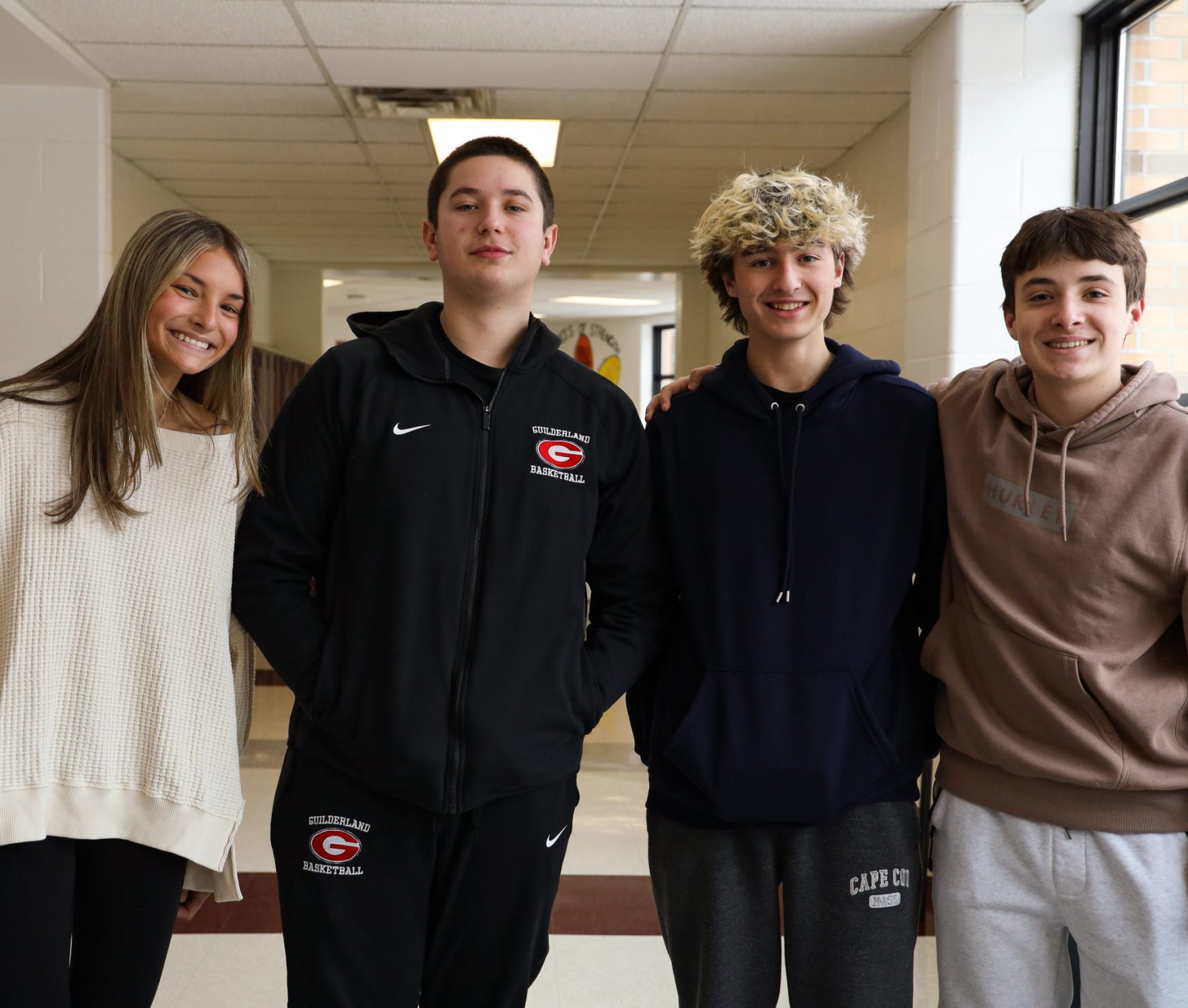 Four GHS students standing together and smiling in the hallway.