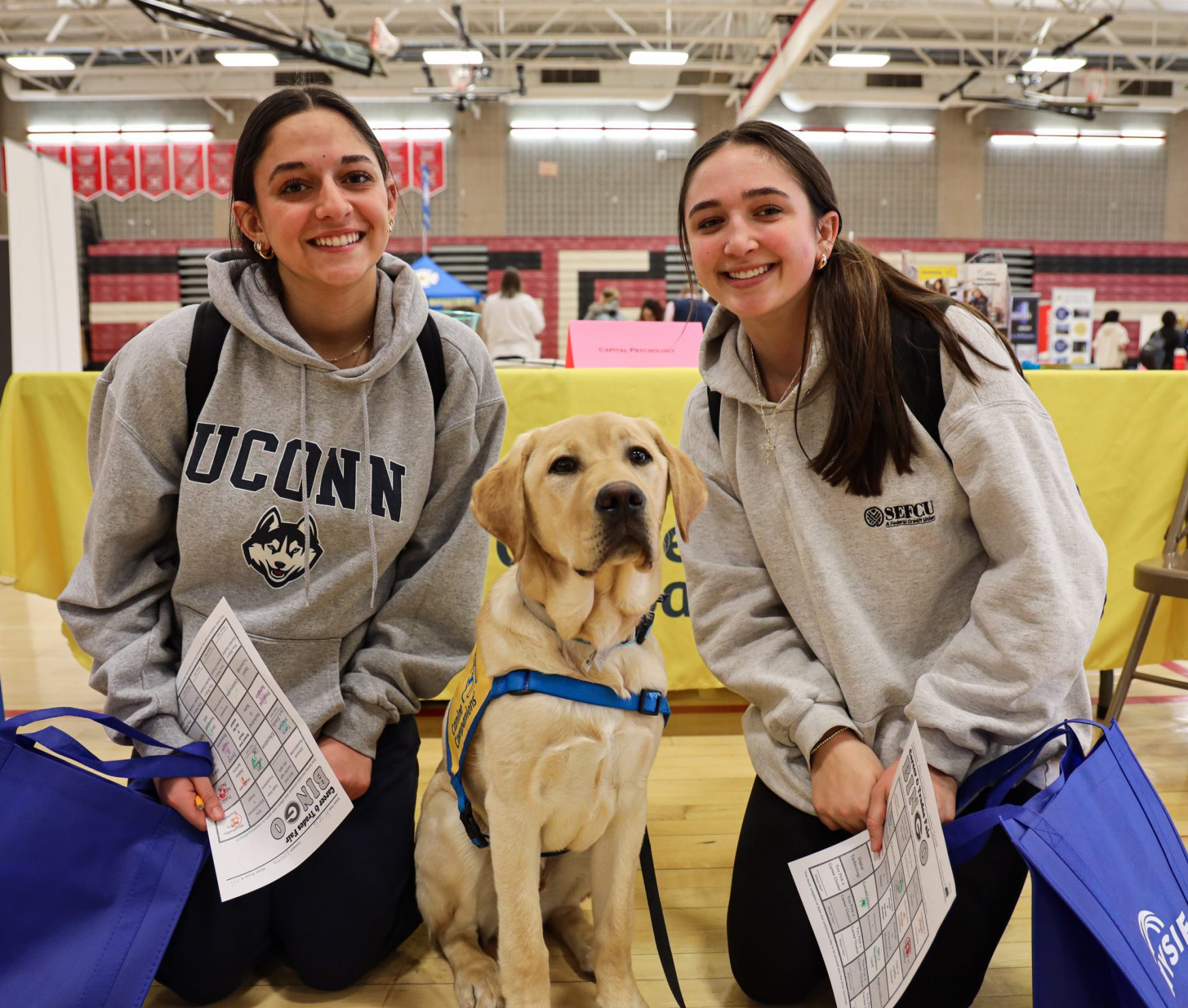 Two students smiling next to a therapy dog.