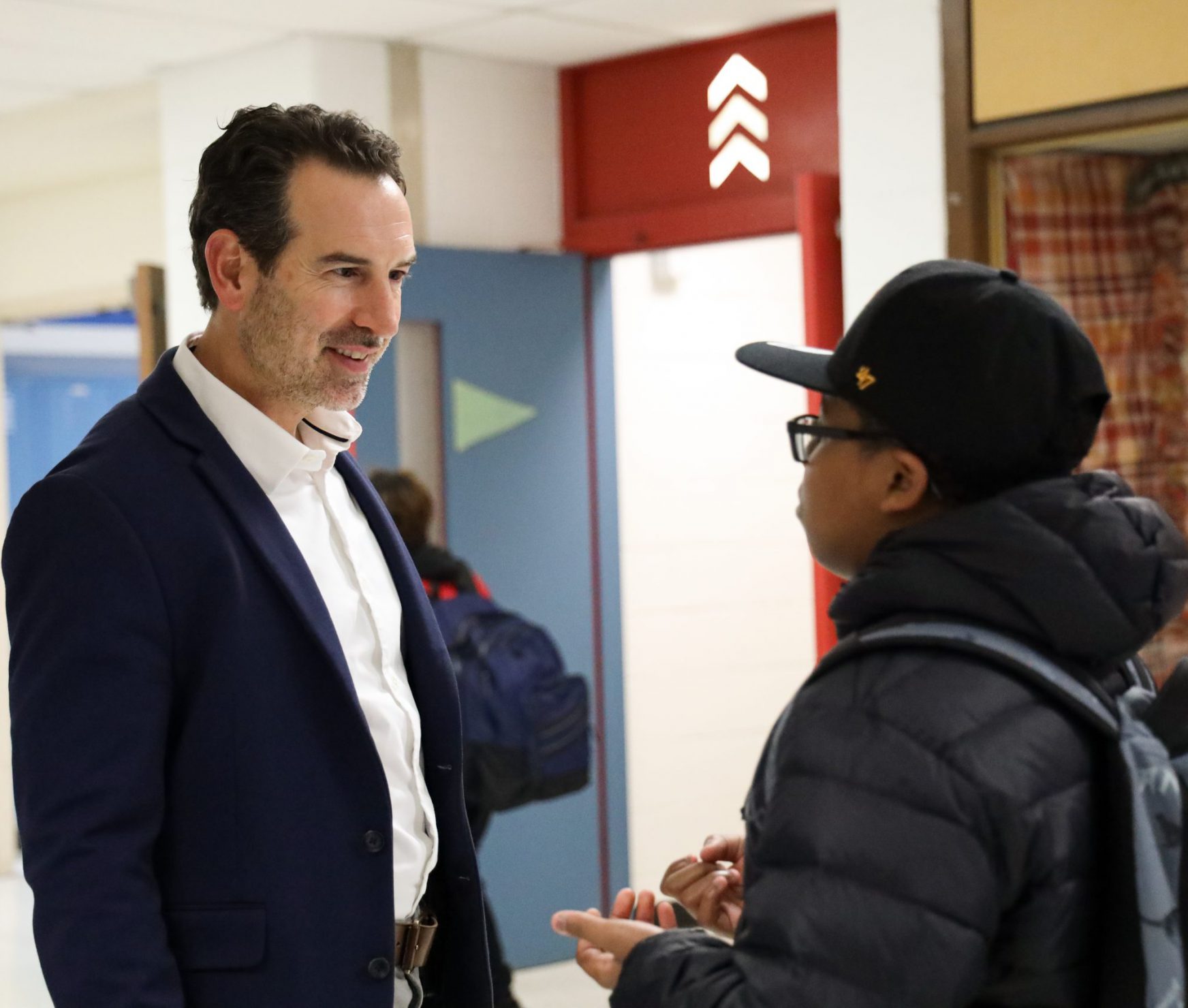 FMS house principal talking with a student in the hallway. They are smiling.