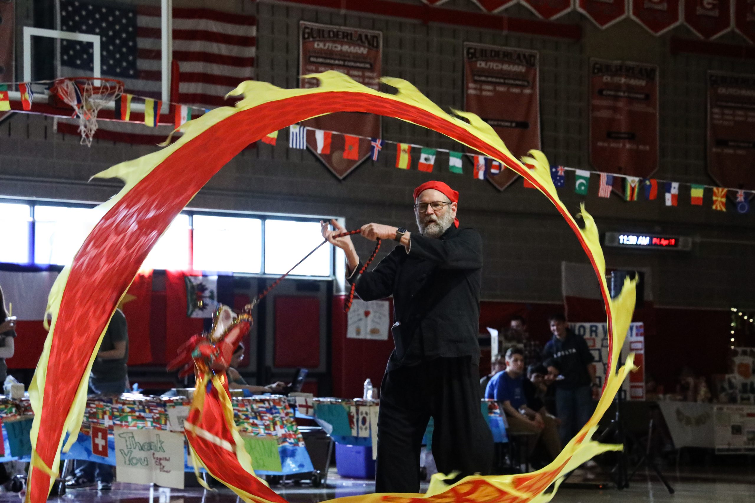 A man is twirling a very long dragon shaped kite-like item.