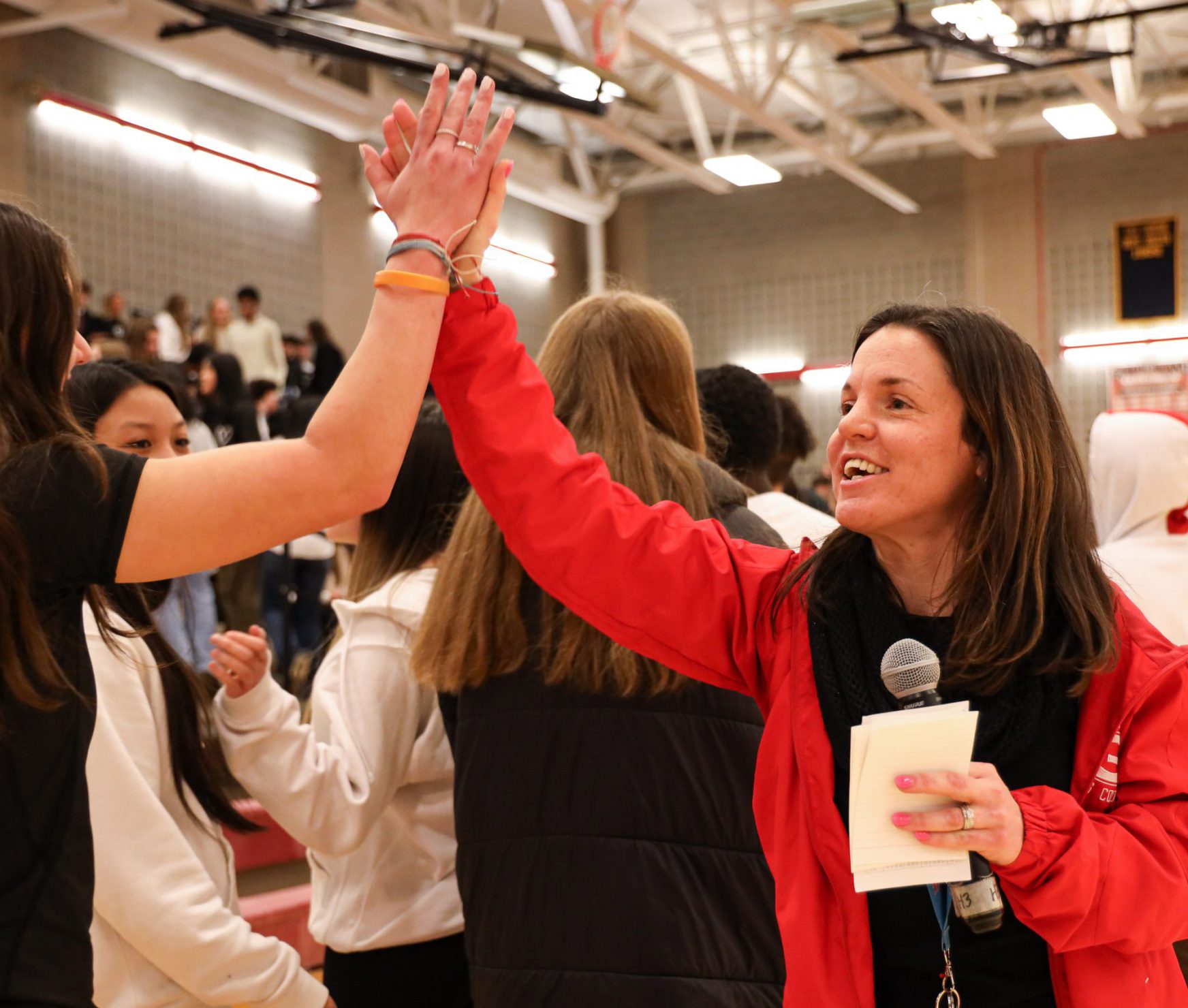 Teacher high fiving a high school student. The teacher is smiling.