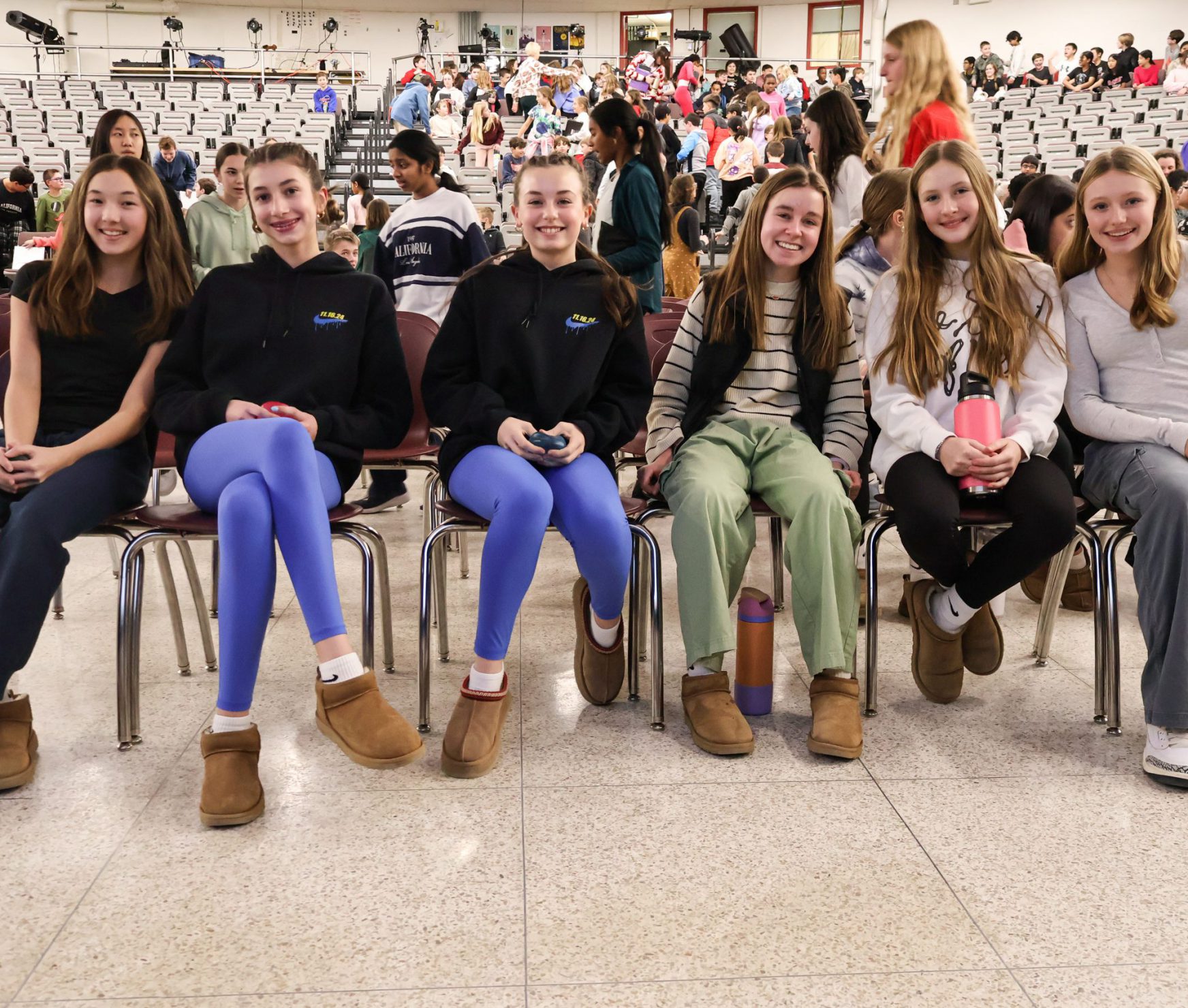 FMS students posing for a photo at an assembly. They are sitting together in a row.