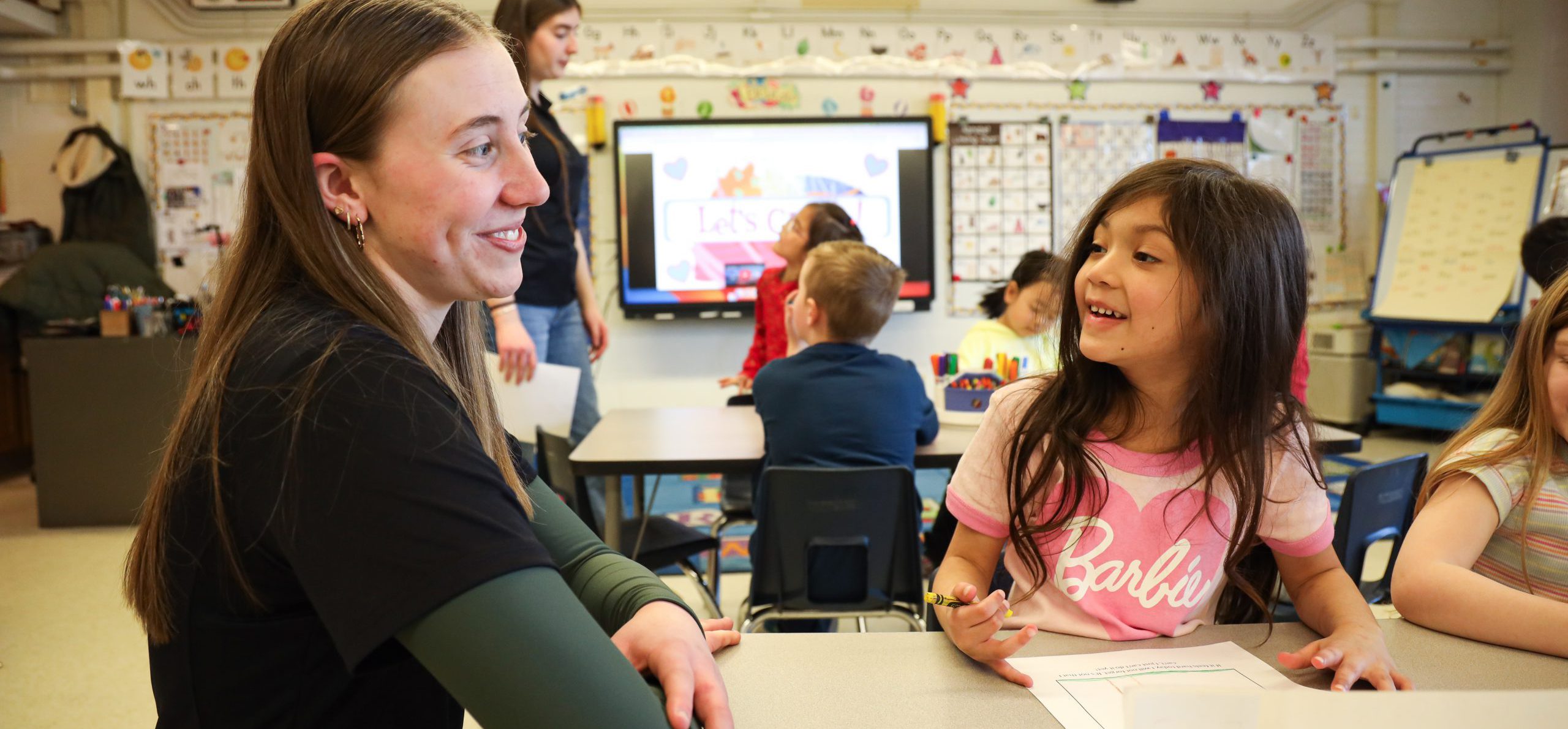 High school student smiling at elementary student.