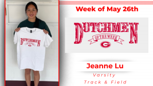 A student athlete stands in front of a white wall holding a white t-shirt with red lettering that reads"Dutchmen of the Week"