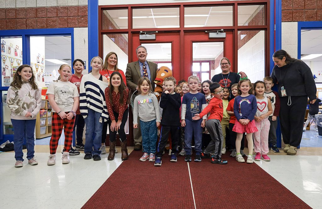 A group photo of elementary students, several teachers and school principal smiling for a photo together.