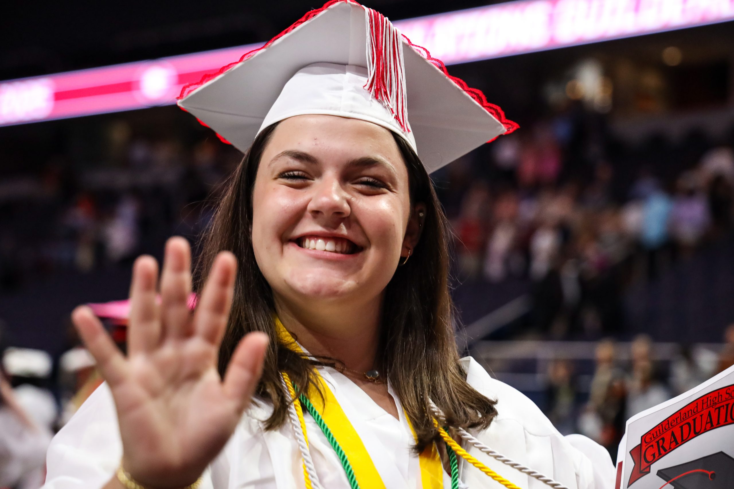 A graduate is waving and smiling