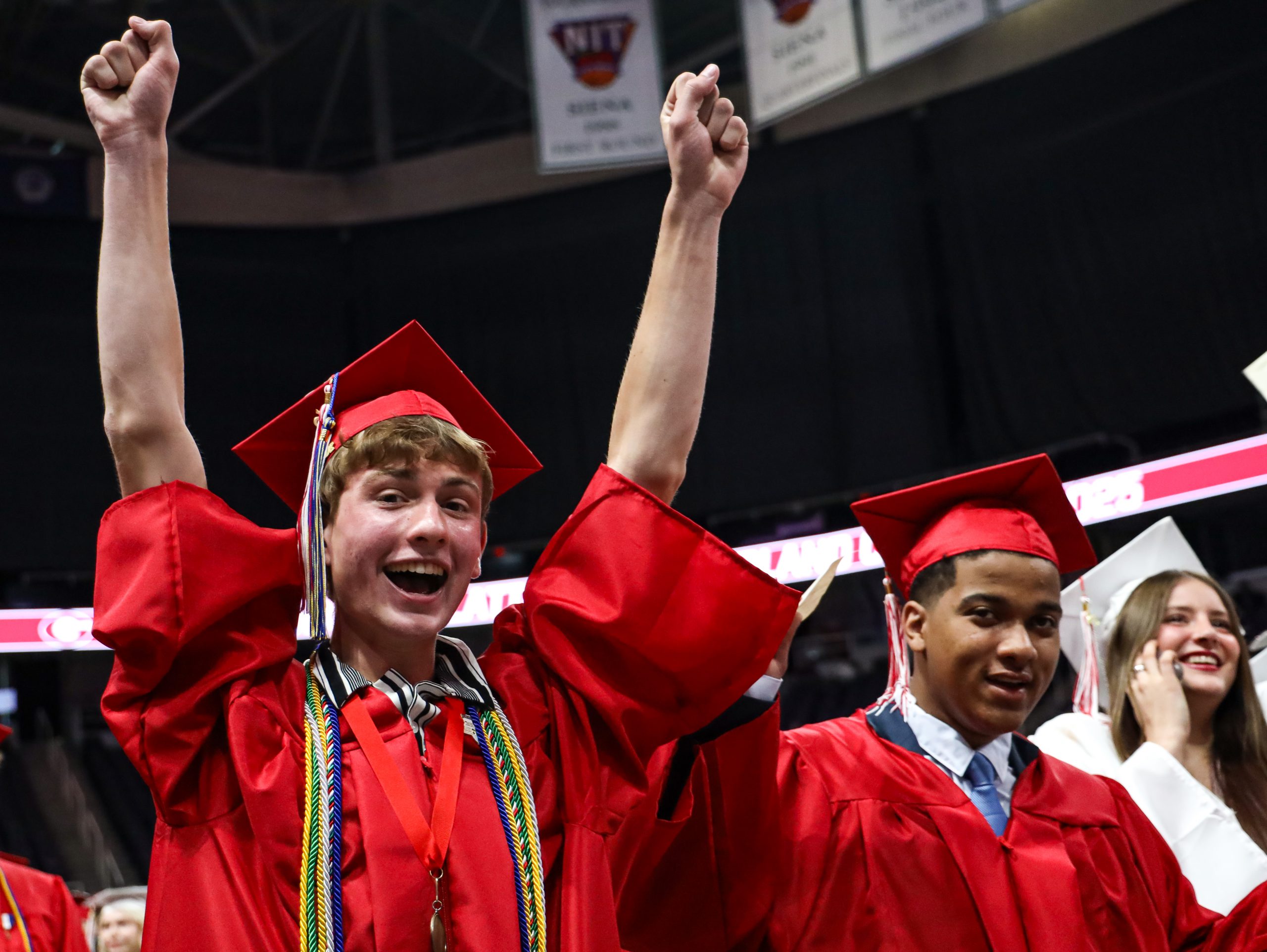 A graduate with arms raised