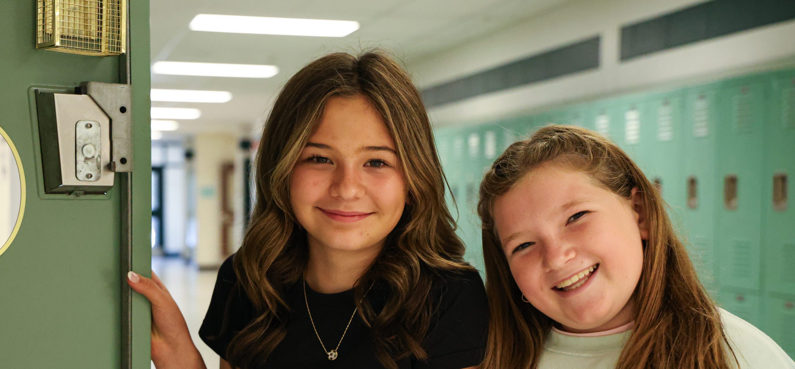 Middle school students smiling next to locker on the first day of school.