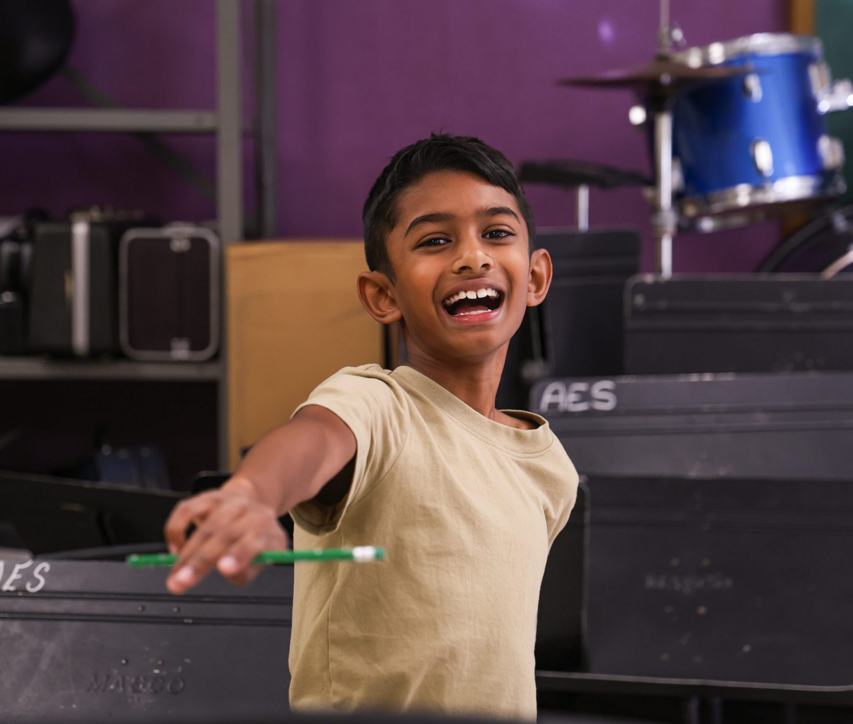 AES student smiling in music class. He is holding a pencil up.